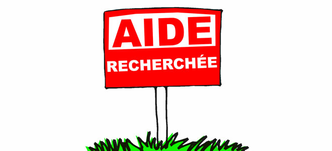 Panneau rouge avec l'inscription "Aide recherchée" planté dans l'herbe, symbolisant le besoin de soutien et de solidarité pour les éleveurs en difficulté, comme Agathe de la ferme de Nouillane, face aux défis des arrêts forcés et au manque de remplaçants dans le secteur agricole.