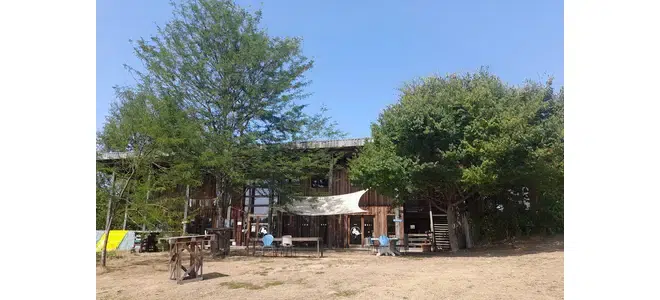 Ancienne ferme du Battement d’ailes à Lauconie, avec bâtiments en bois, arbres autour et cour dégagée sur la colline.