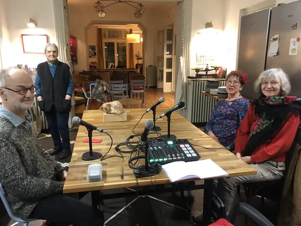 Quatre personnes âgées souriantes autour d'une table avec des micros à la Coloc Marbeau, lors du passage de Radio Grand Brive.