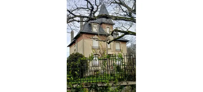 Maison ancienne à tour et toit d'ardoise, volets blancs fermés, derrière une grille en fer forgé envahie de lierre. Lieu de mémoire de la Résistance et refuge de familles juives à Saint-Martin-la-Méanne.