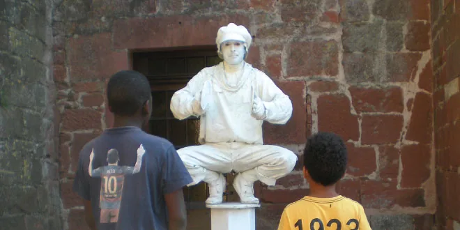 Photographie de deux enfants devant une statue blanche