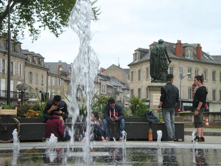 Photographie d'une place avec une fontaine et une statue