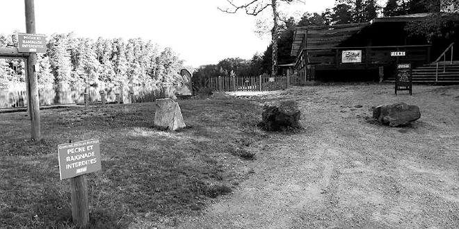 Photographie en noir et blanc d'un chemin de campagne avec un panneau