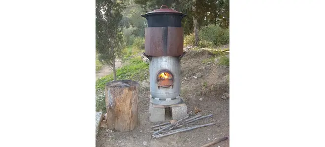 Photo : un rocket stove en tôle, fagots de bois à proximité