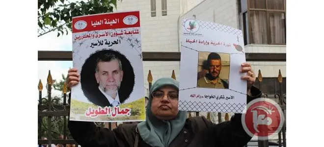 Photo : un homme tenant l’affiche d’un prisonnier palestinien