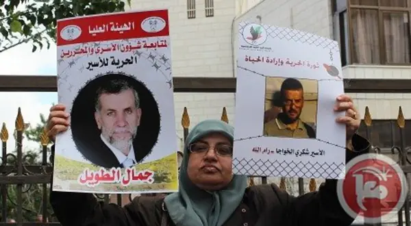 Photo : un homme tenant l’affiche d’un prisonnier palestinien