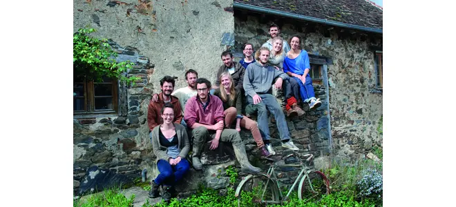Photographie du groupe de paysans de la ferme collective de la Tournerie, devant un bâtiment en pierre.