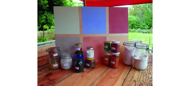 Photographie de pots de peinture et de graines sur une table.