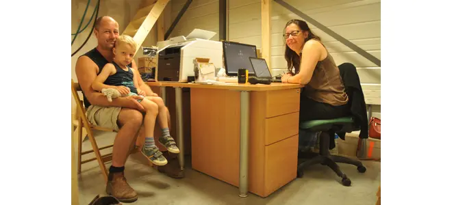Photographie de l’équipe de la Biocoop de Malemort, un adulte et un enfant devant un bureau.