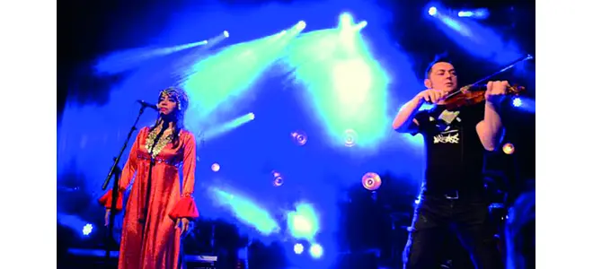 Photographie d’Orange Blossom en concert aux Sables, avec des musiciens sur scène.