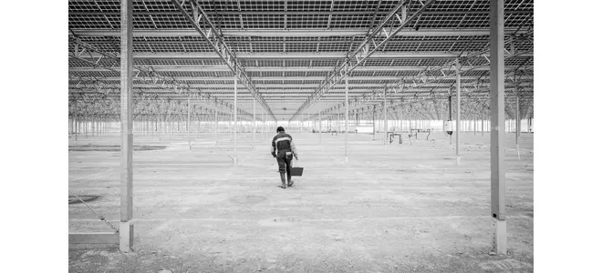 Sous les serres photovoltaïques du site des Marottières (Maine-et-Loire) : une vaste structure métallique vide, une personne au loin