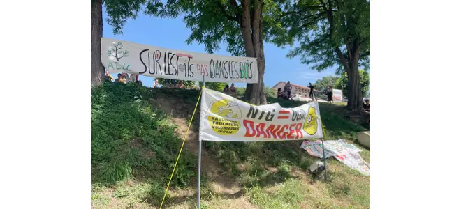 Banderole « Stop Saint-Hilaire photovoltaïque » accrochée devant un pré et des arbres, à Saint-Hilaire-Foissac