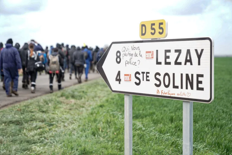 Photographie de manifestants devant le panneau « Lezay / Sainte-Soline »